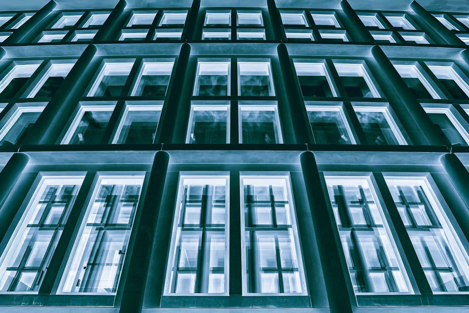 Una retícula de ventanas iluminadas en la fachada de un edificio al anochecer